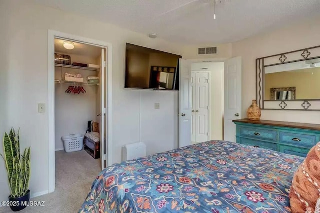 bedroom featuring a walk in closet, light colored carpet, and a closet
