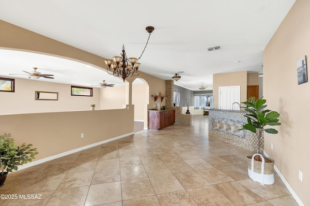 hall featuring an inviting chandelier, plenty of natural light, and light tile patterned flooring