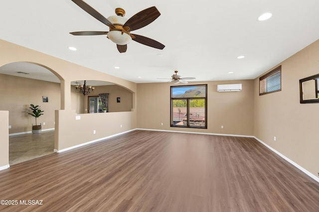 unfurnished living room featuring hardwood / wood-style flooring, a chandelier, and a wall mounted AC