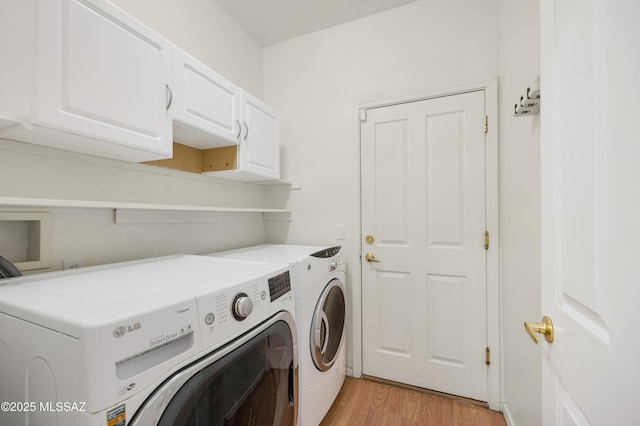 washroom featuring separate washer and dryer, light hardwood / wood-style flooring, and cabinets