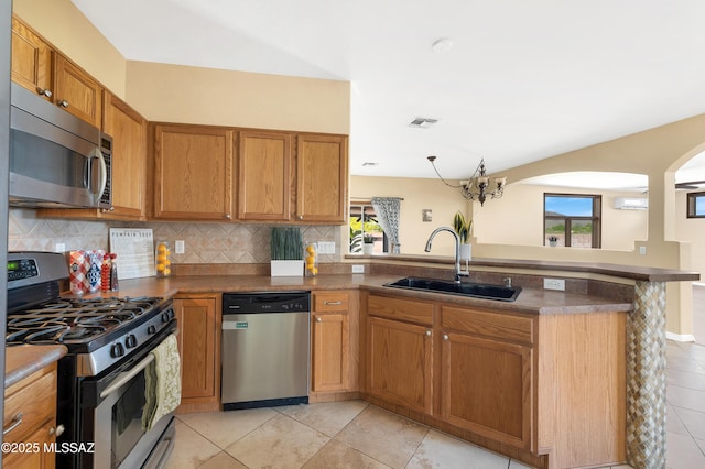 kitchen featuring tasteful backsplash, sink, stainless steel appliances, and kitchen peninsula