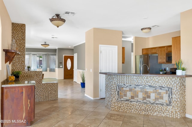 kitchen with light tile patterned flooring, ornamental molding, and stainless steel appliances