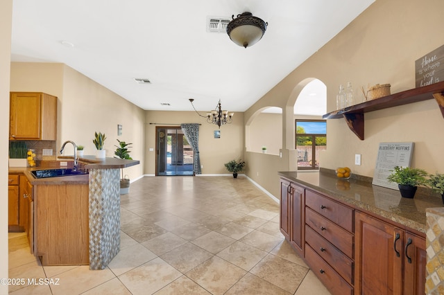 kitchen featuring light tile patterned flooring, a healthy amount of sunlight, sink, and backsplash