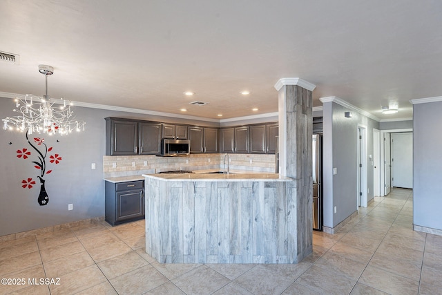 kitchen with light tile patterned flooring, ornamental molding, a kitchen island with sink, and backsplash