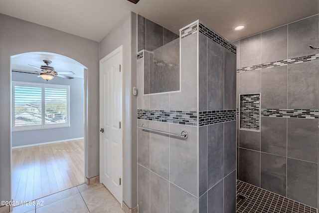 bathroom featuring tile patterned flooring, a tile shower, and ceiling fan