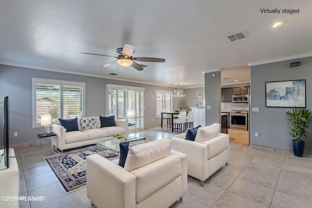 living room with light tile patterned flooring, ceiling fan, ornamental molding, and a wealth of natural light