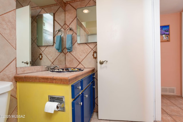 half bathroom with tile patterned flooring, visible vents, tile walls, and vanity