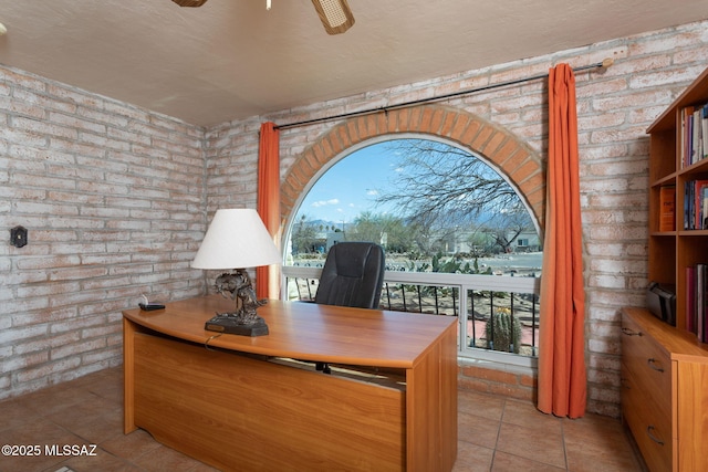 office area featuring tile patterned flooring, a healthy amount of sunlight, ceiling fan, and brick wall