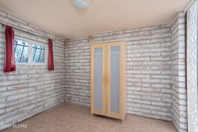 interior space with brick wall and light tile patterned floors