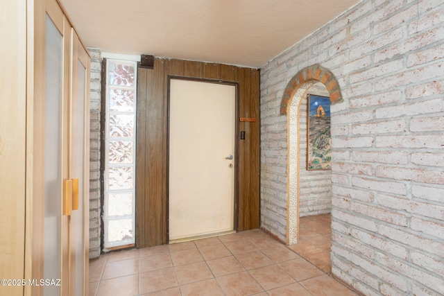 interior space featuring light tile patterned floors and brick wall