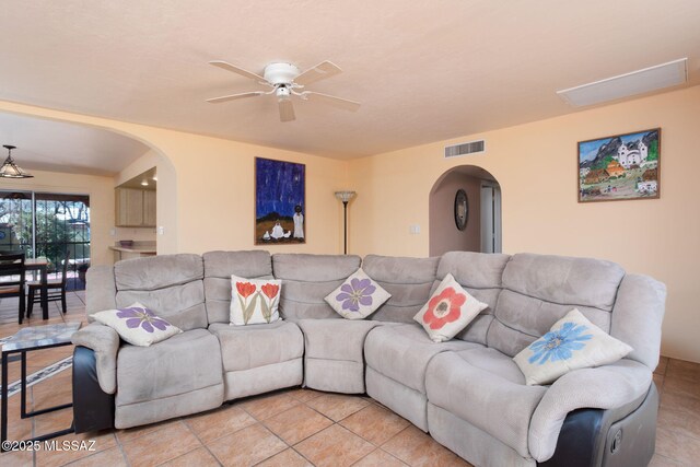 living room with arched walkways, visible vents, and a ceiling fan