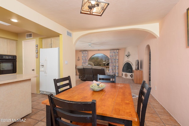 dining space featuring arched walkways, visible vents, and a ceiling fan