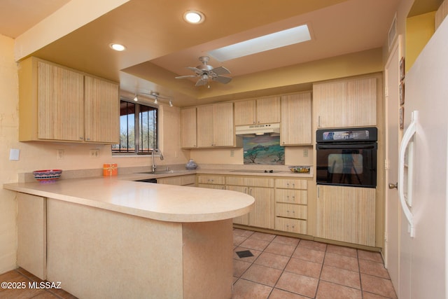 kitchen with under cabinet range hood, light countertops, black appliances, light brown cabinets, and a sink