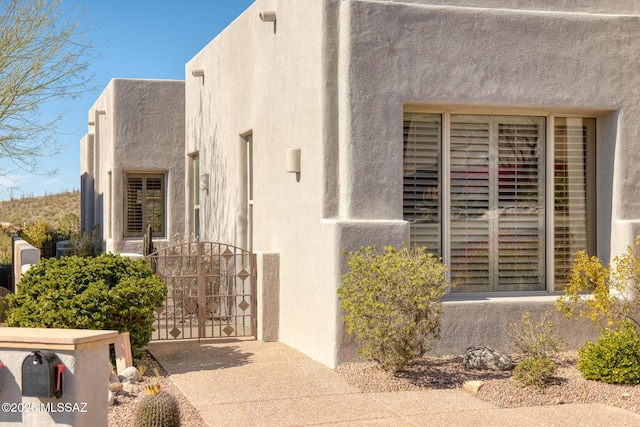 view of exterior entry with a gate and stucco siding