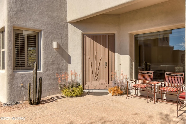 entrance to property featuring a patio area and stucco siding