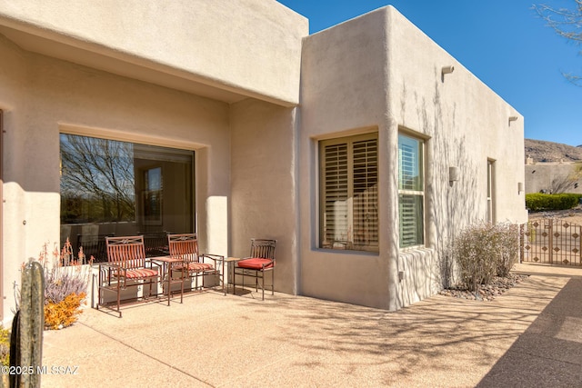 entrance to property with a patio area, fence, and stucco siding