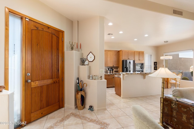 kitchen featuring stainless steel fridge, visible vents, a kitchen breakfast bar, black microwave, and recessed lighting