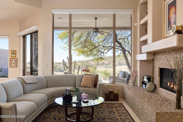 living area with ceiling fan, a fireplace, and a healthy amount of sunlight