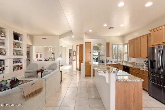 kitchen featuring light tile patterned floors, built in shelves, visible vents, open floor plan, and stainless steel fridge