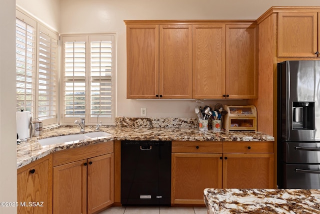 kitchen with dishwasher, light stone counters, a sink, and stainless steel fridge with ice dispenser