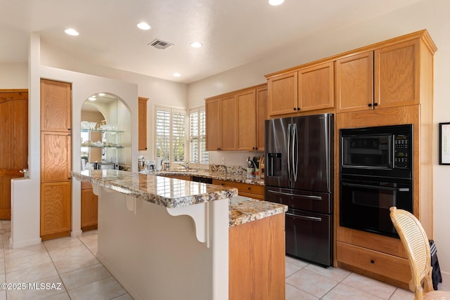 kitchen with light tile patterned floors, visible vents, black appliances, and light stone countertops