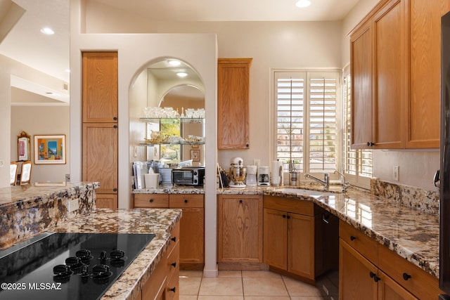 kitchen with recessed lighting, light tile patterned flooring, a sink, light stone countertops, and black appliances