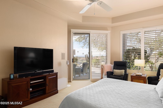 bedroom featuring light carpet, ceiling fan, a tray ceiling, and access to exterior