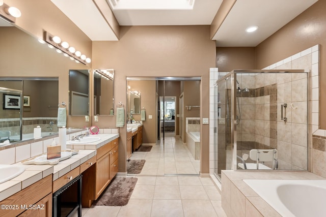 bathroom with double vanity, tile patterned floors, a garden tub, a shower stall, and a sink