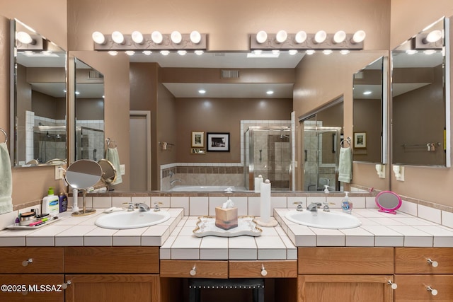 bathroom featuring visible vents, a sink, a shower stall, and double vanity