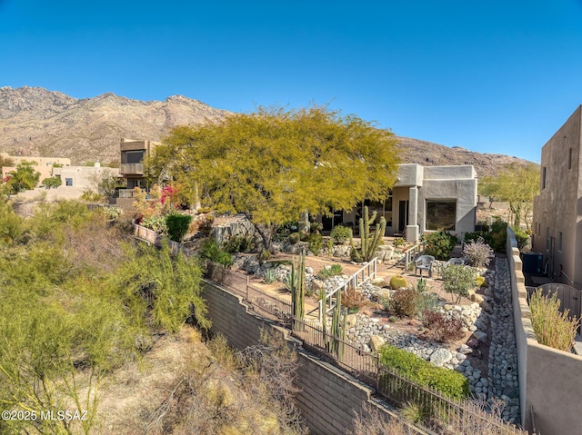 exterior space featuring fence, a mountain view, and stucco siding