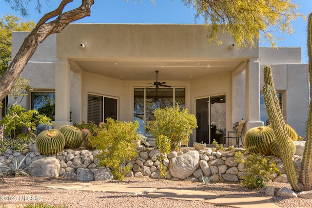 rear view of house with a ceiling fan and stucco siding