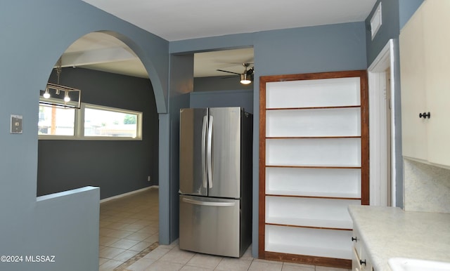 kitchen with white cabinets, light tile patterned floors, stainless steel fridge, and ceiling fan