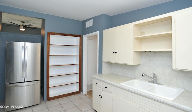 kitchen featuring sink, stainless steel refrigerator, ceiling fan, white cabinets, and light tile patterned flooring