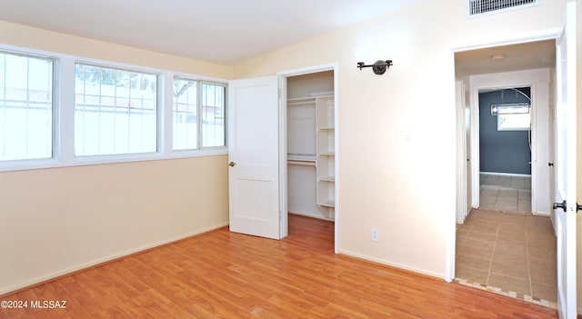 unfurnished bedroom featuring a walk in closet, a closet, and light wood-type flooring