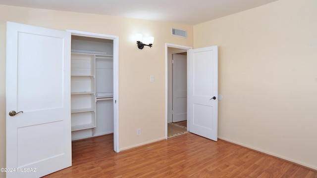 unfurnished bedroom featuring a spacious closet, hardwood / wood-style floors, and a closet