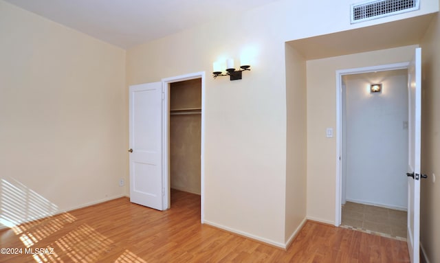 unfurnished bedroom featuring a walk in closet, a closet, and light wood-type flooring