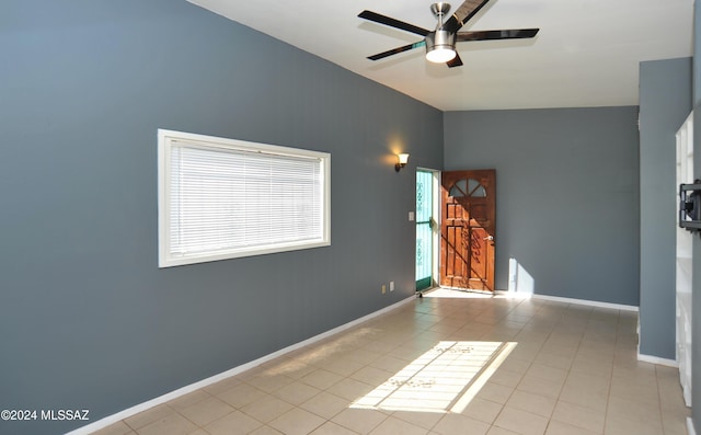 unfurnished room featuring ceiling fan, vaulted ceiling, and light tile patterned floors