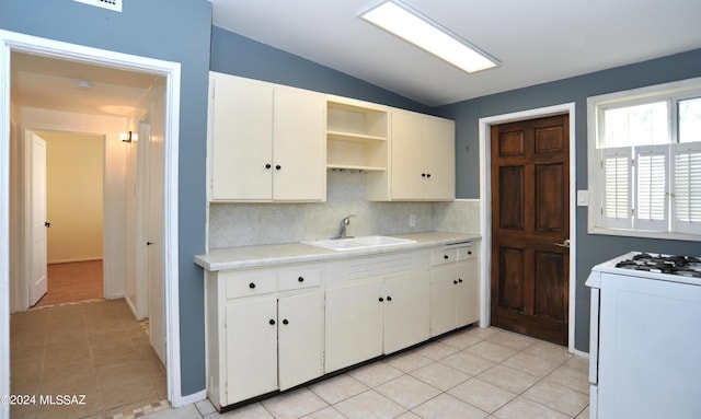 kitchen featuring sink, white gas range oven, tasteful backsplash, white cabinets, and vaulted ceiling