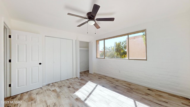 unfurnished bedroom featuring ceiling fan, brick wall, and light hardwood / wood-style floors