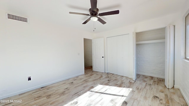 unfurnished bedroom with ceiling fan, brick wall, and light hardwood / wood-style floors