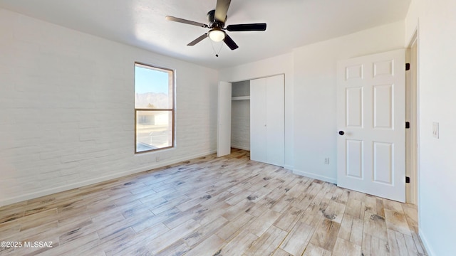 unfurnished bedroom featuring ceiling fan, light hardwood / wood-style floors, and a closet