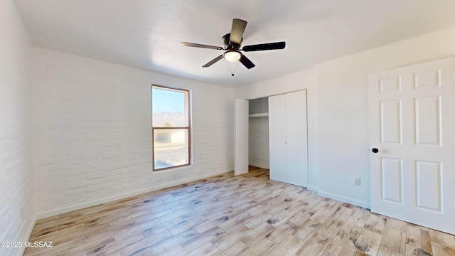 unfurnished bedroom featuring ceiling fan, light hardwood / wood-style floors, and a closet