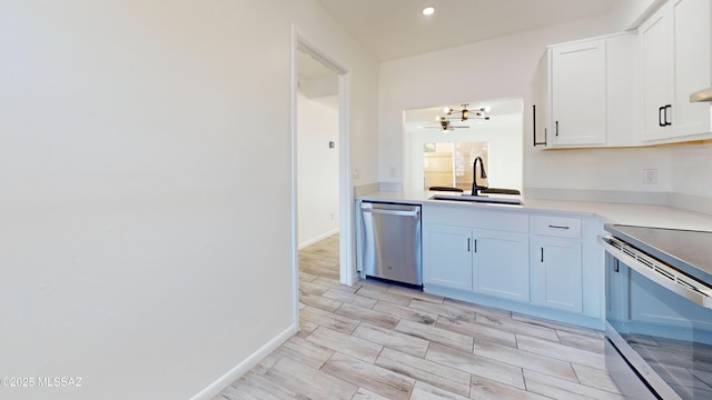 kitchen featuring stainless steel appliances, sink, white cabinets, and ceiling fan