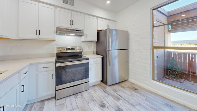 kitchen featuring stainless steel appliances, white cabinets, light hardwood / wood-style floors, and a skylight