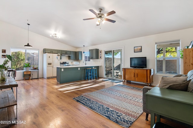 living room featuring lofted ceiling, sink, ceiling fan, and light hardwood / wood-style flooring