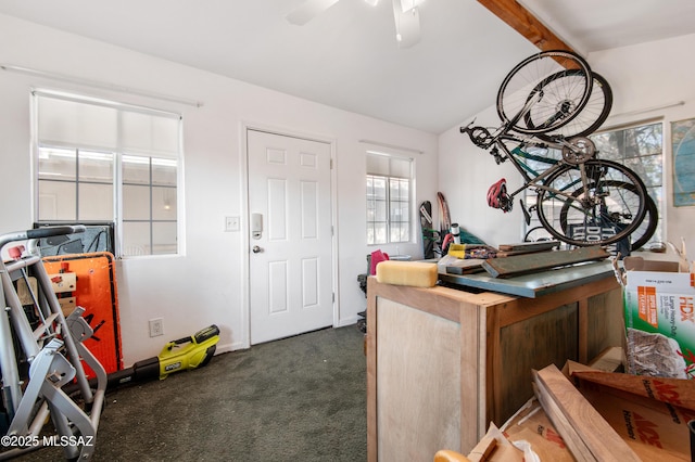 interior space featuring lofted ceiling with beams, ceiling fan, and dark carpet