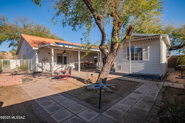 rear view of property with ceiling fan and a patio area