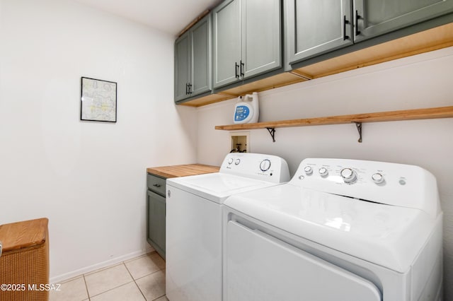 laundry room with light tile patterned flooring, cabinets, and washing machine and clothes dryer