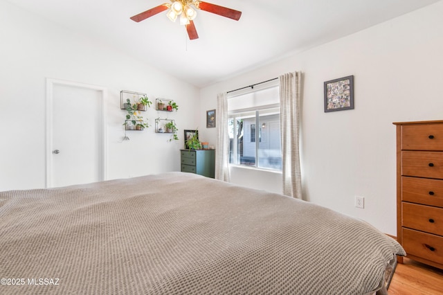 bedroom with ceiling fan, light hardwood / wood-style floors, and vaulted ceiling