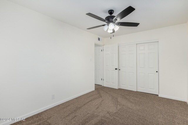 unfurnished bedroom featuring carpet, ceiling fan, and a closet